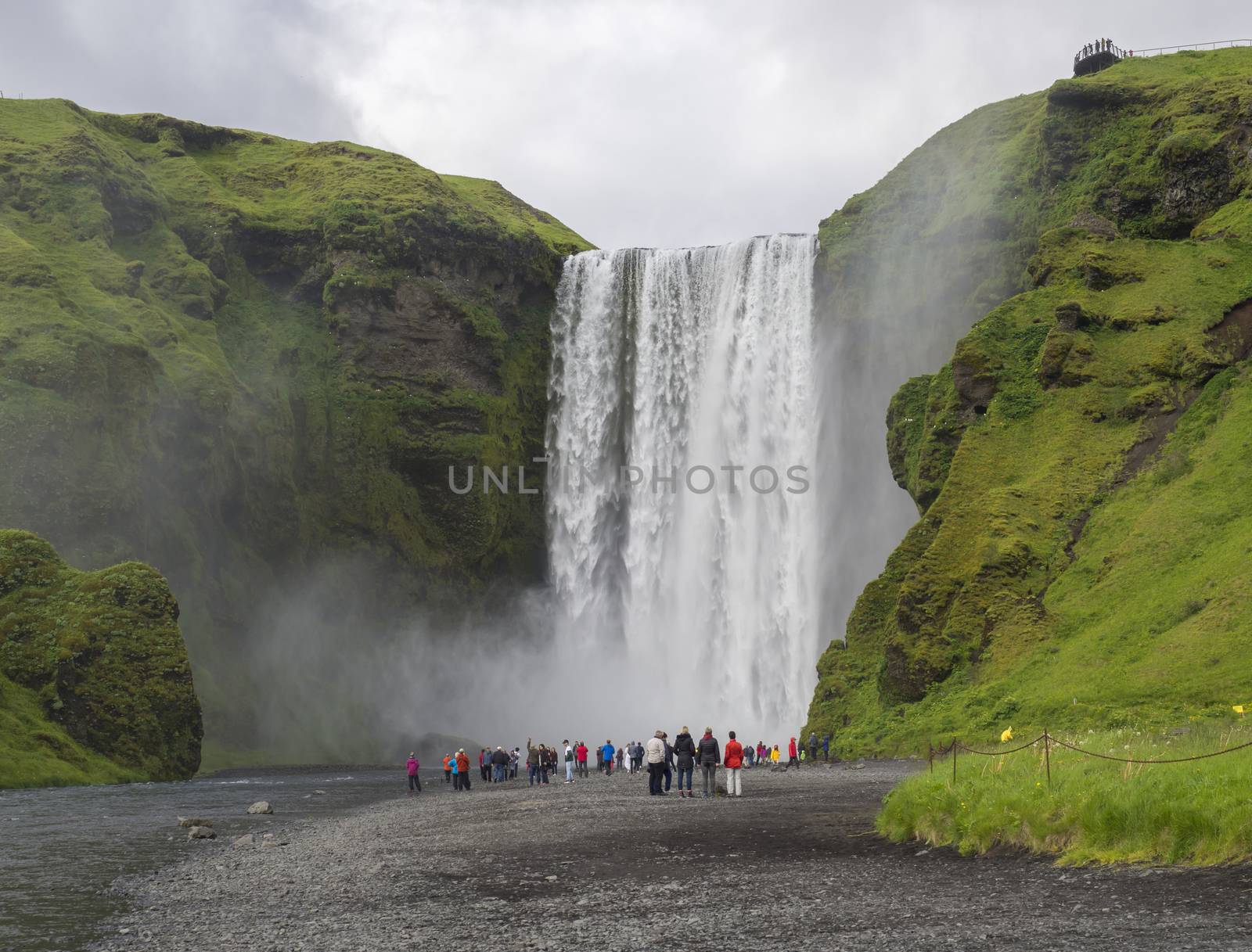 Beautiful Skogafoss waterfall in South Iceland Skogar with group of colorful dressed tourist people by Henkeova