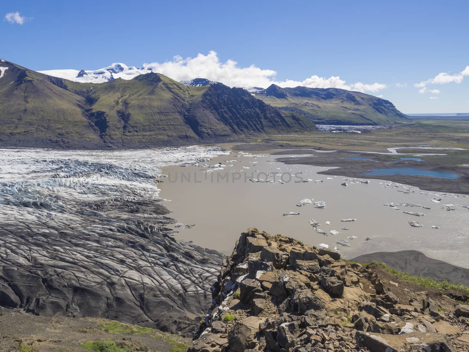 View on glacier lagoon with icebergs and tongue of Skaftafellsjokull, Vatnajokull spur, valley Morsardalur river and colorful rhyolit mountains in Skaftafell national park, Iceland