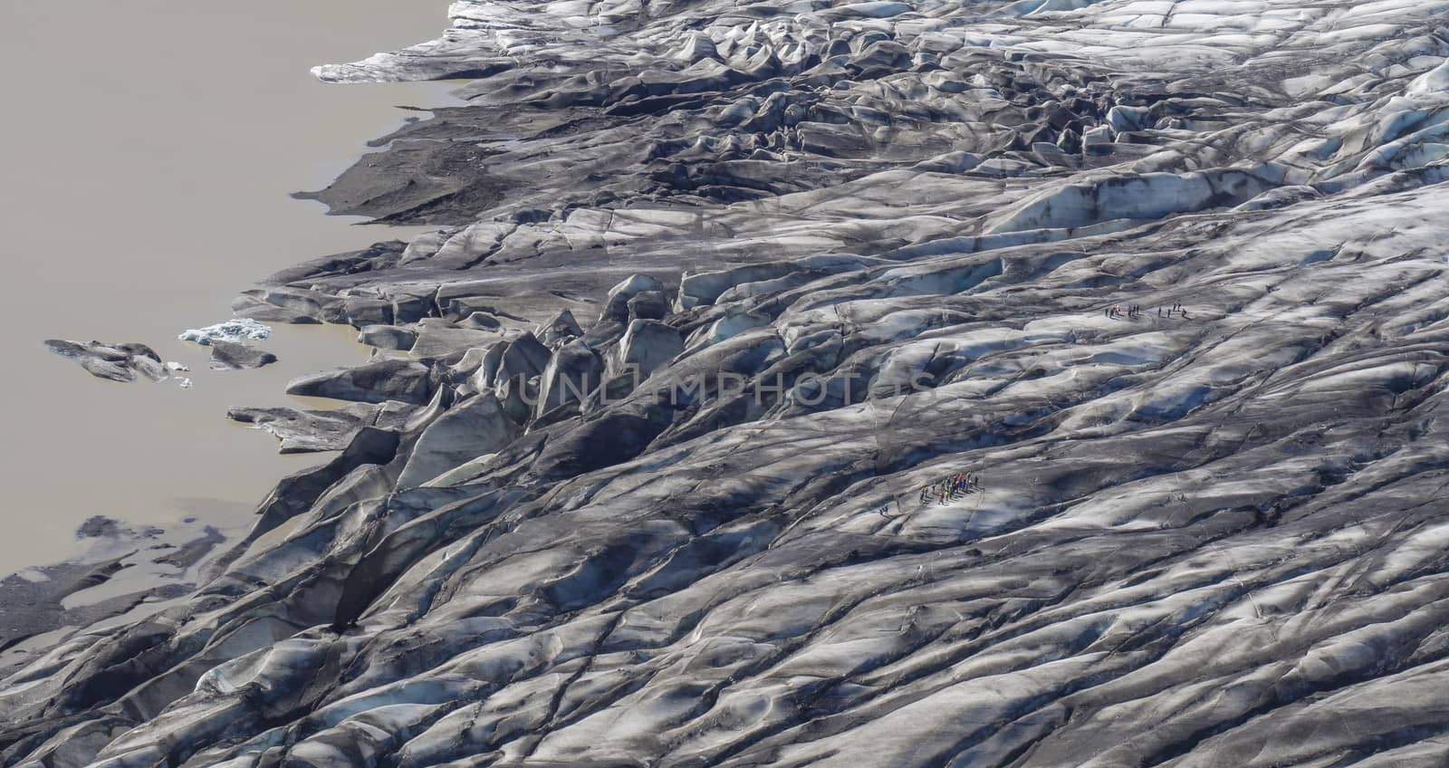 Colorful group of tourist people on glacier walk at tongue of Skaftafellsjokull glacier, Vatnajokull spur, in Skaftafell national park, Iceland