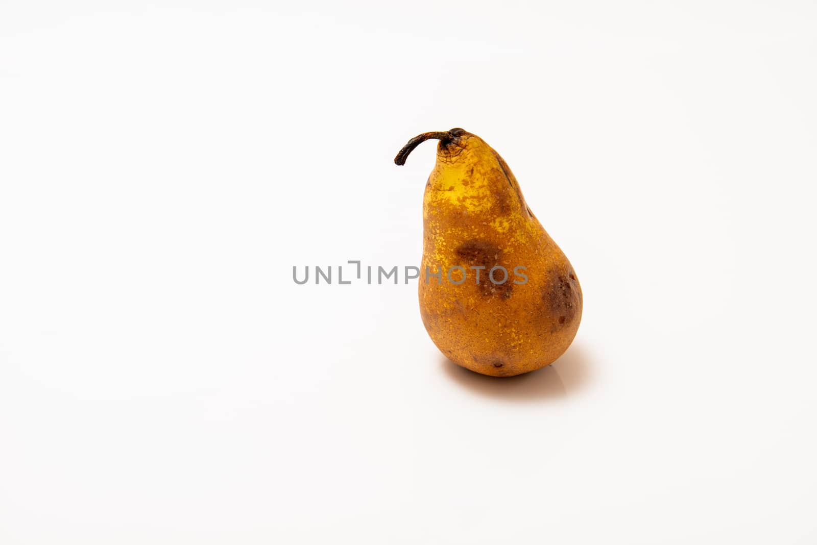 overripe pear with dark spots on a white background