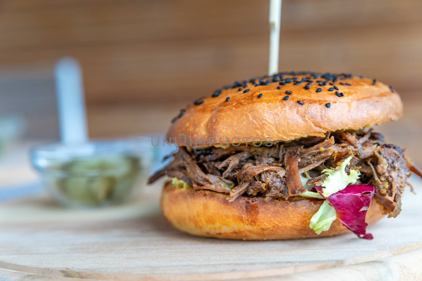 hamburger with shredded beef on a wooden board.
