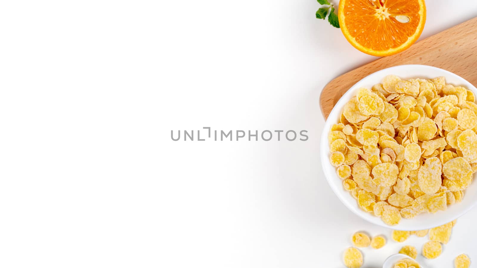 Corn flakes bowl sweeties with milk and orange on white background, top view, flat lay overhead layout, fresh and healthy breakfast design concept.