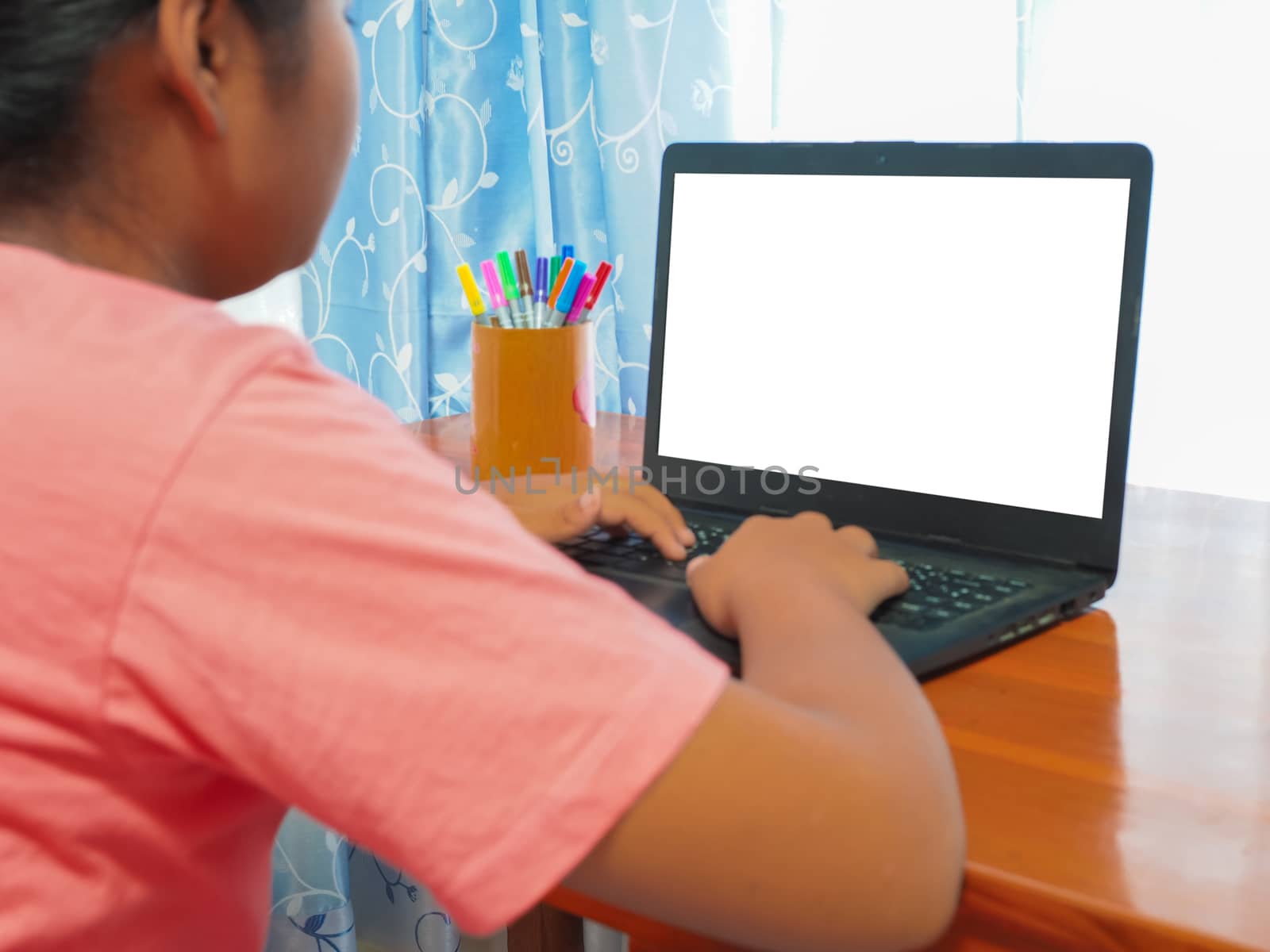 A girl sitting and watching the computer screen online learning by Unimages2527