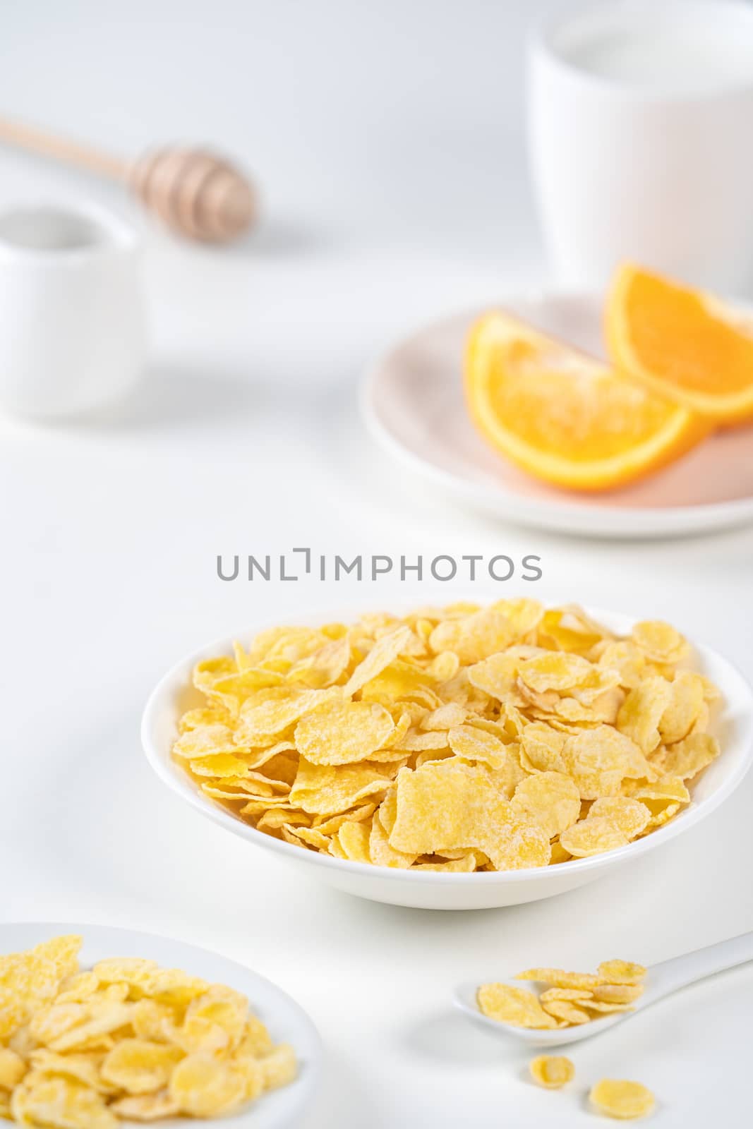 Corn flakes bowl sweeties with milk and orange on white background, close up, fresh and healthy breakfast design concept.