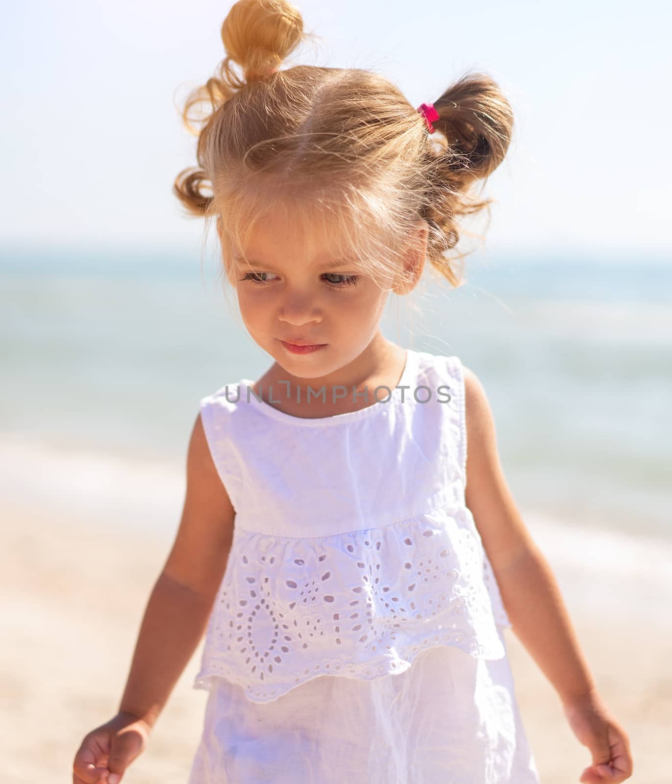 Little Caucasian girl 3 years old walks along the sea coast. Cute child portrait on the beach. Family vacation Summer season