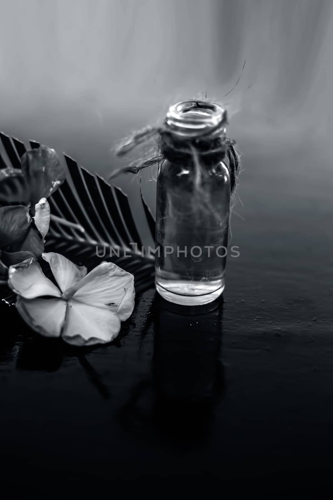 Herbal and floral essence or concentration made from Rosmarinus officinalis also known as rosemarry flower in a glass bottle on wooden surface.