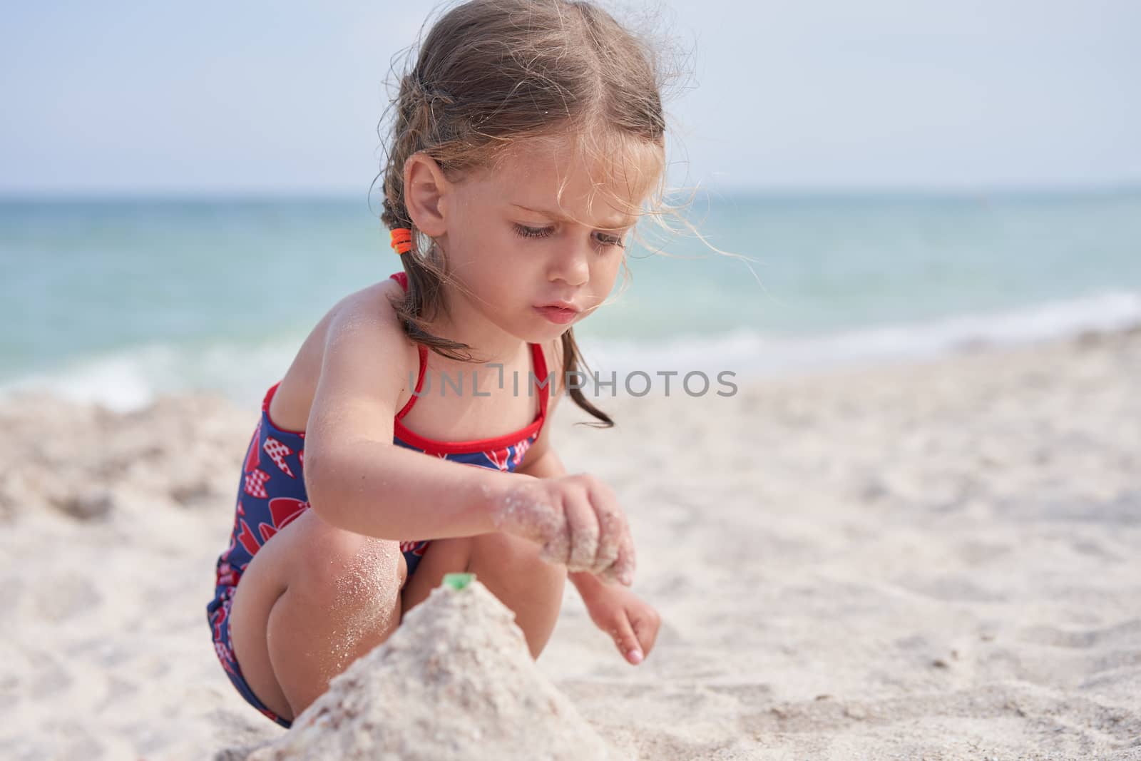 Child playing sand beach Little girl play sad alone summer family vacation Caucasian female 3 years old dressed baby swimwear near sea water