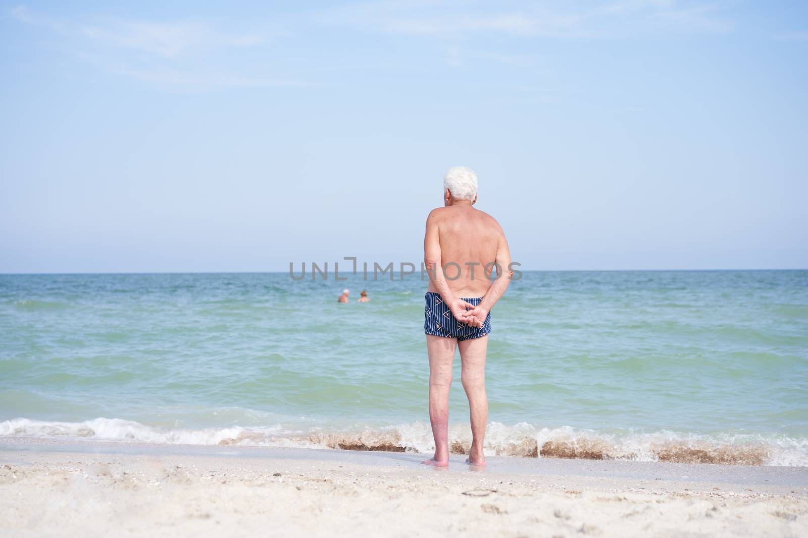 Alone unrecognizable senior man standing sea beach watching horizon rear view Sadness loneliness ageing solitude aged