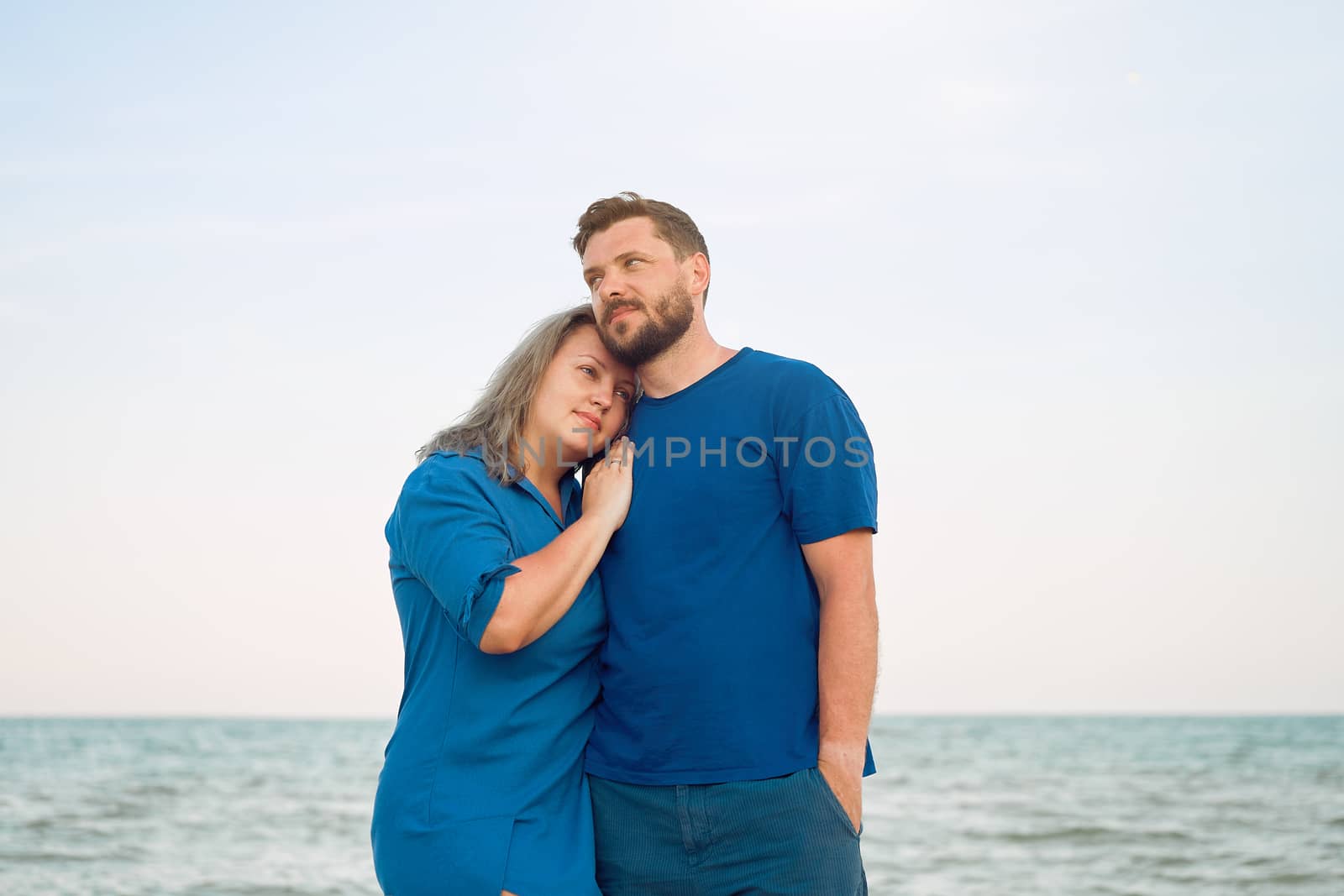 Man hugging woman standing sea beach. Romantic relationship on summer vacation by andreonegin