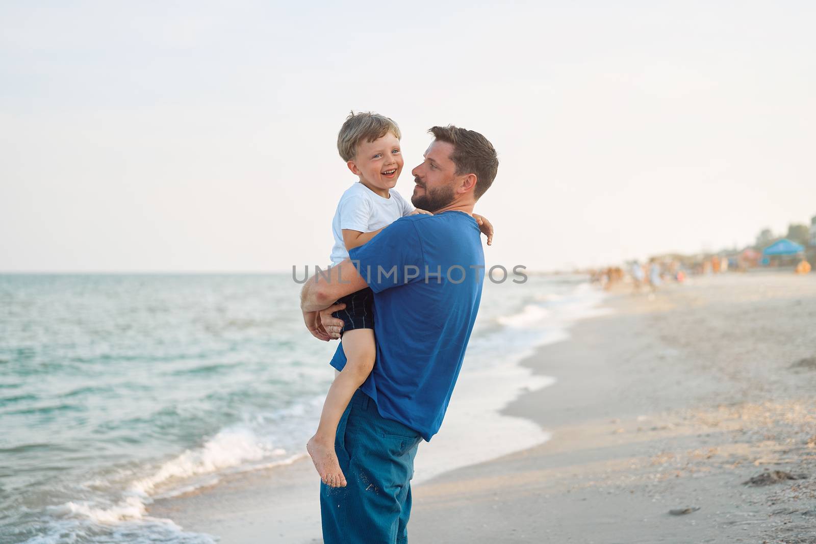 Father son spending time together sea vacation Young dad child little boy walking beach Fathers day. Family with one child. Happy childhood with daddy. sitting on hands laughs
