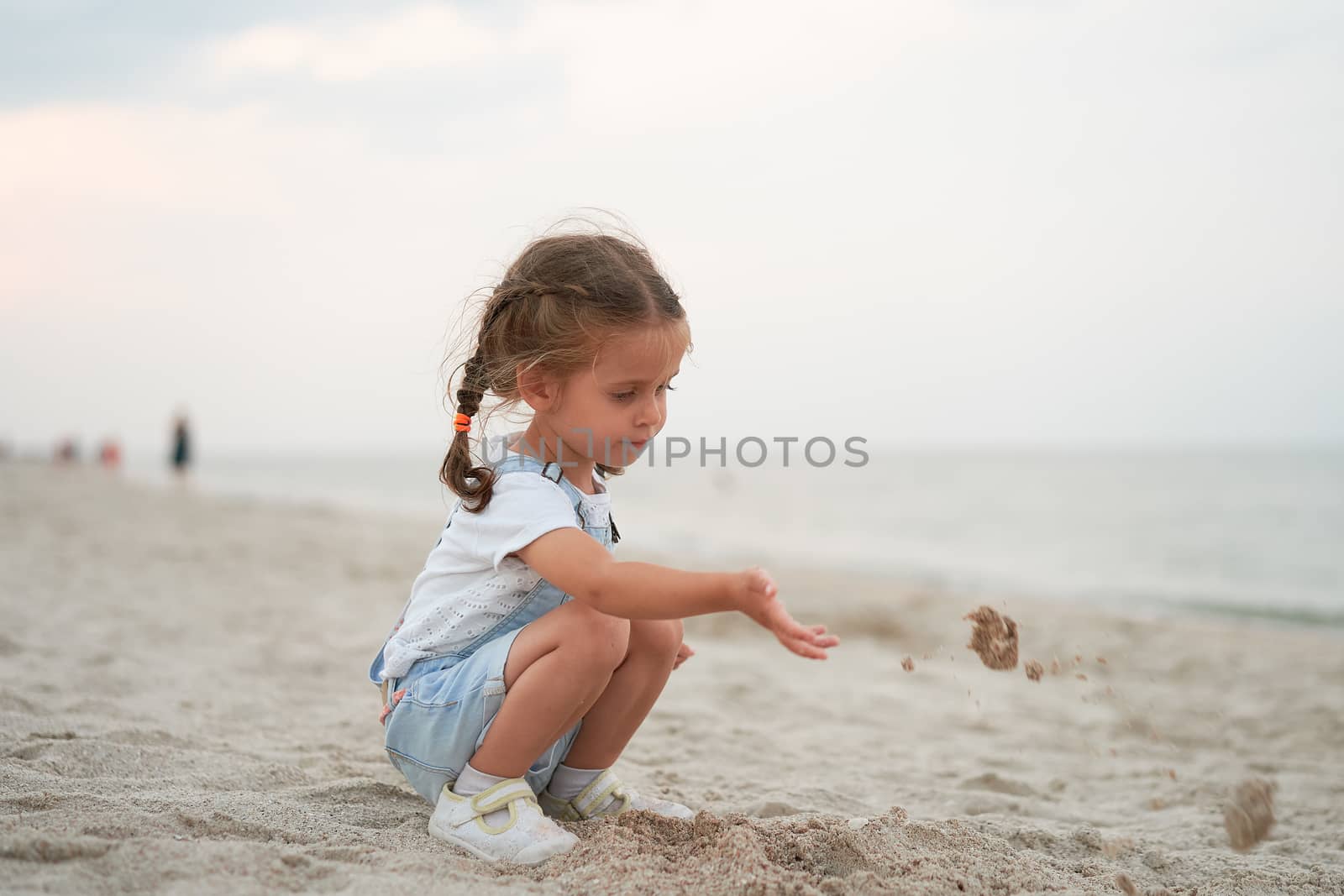 Child playing sand beach Little girl play sad alone summer family vacation Caucasian female 3 years old dressed denim near sea water
