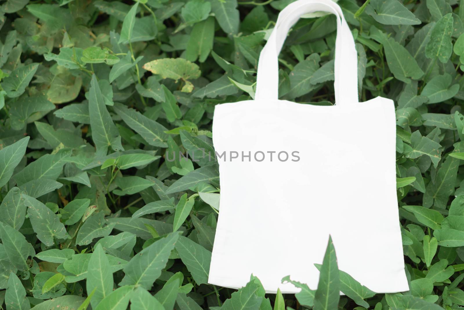 Closeup white bag canvas fabric on green grass background, Save the world concept