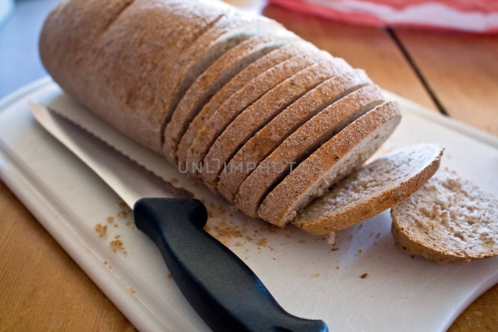 Breakfast time. Wheat bread on cutting board with knife.