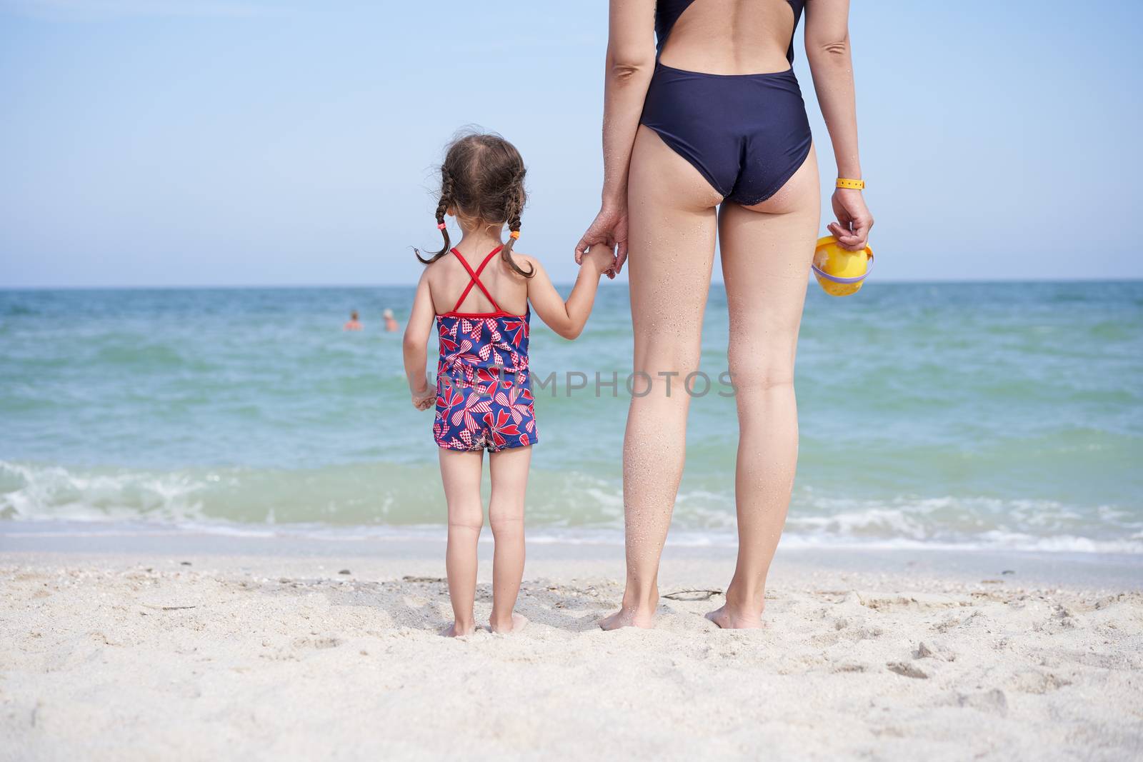 Mother daughter beach together rear view Unrecognizable caucasian woman little girl swimwear standing seaside back. by andreonegin