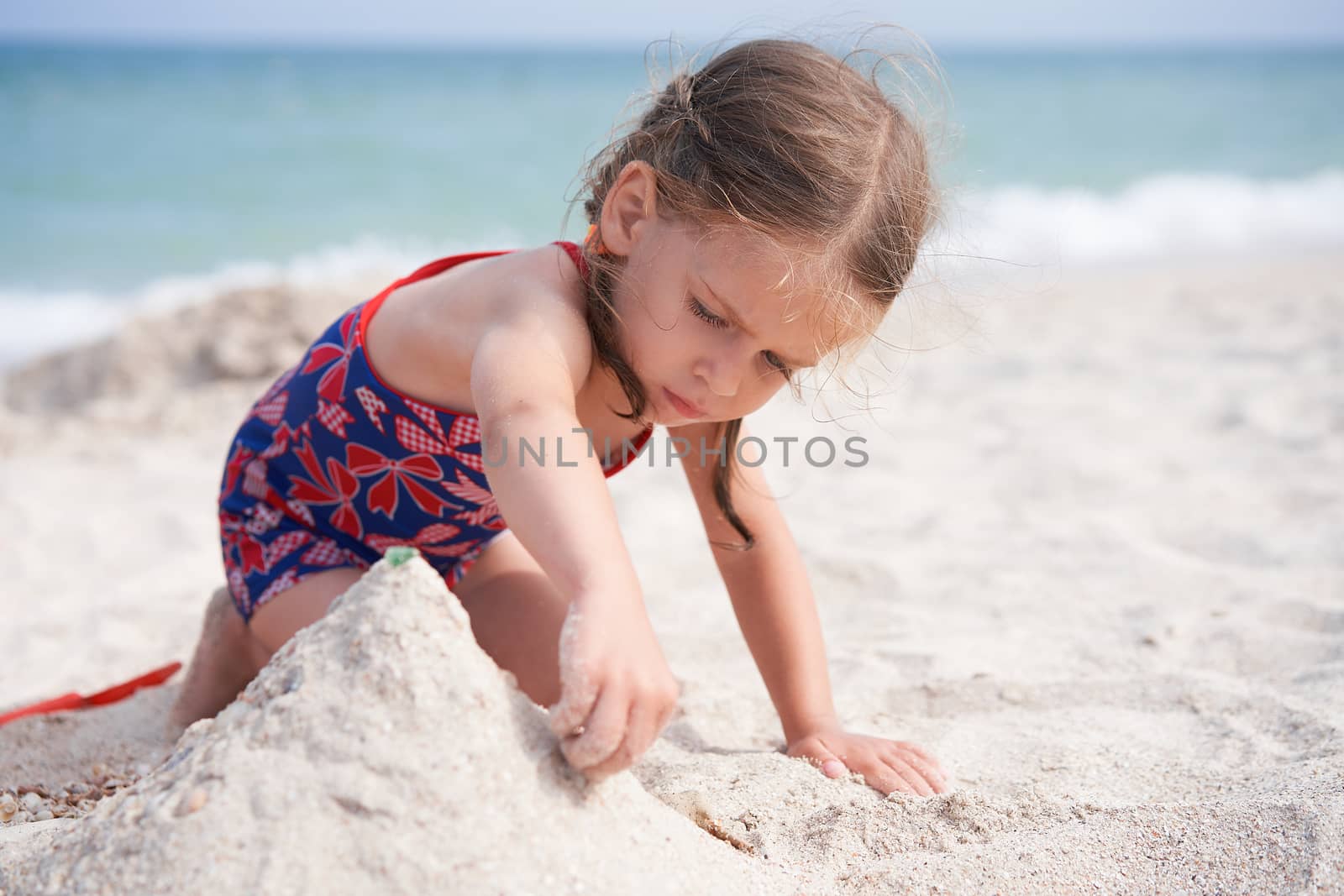 Child playing sand beach Little girl play sad alone summer family vacation by andreonegin