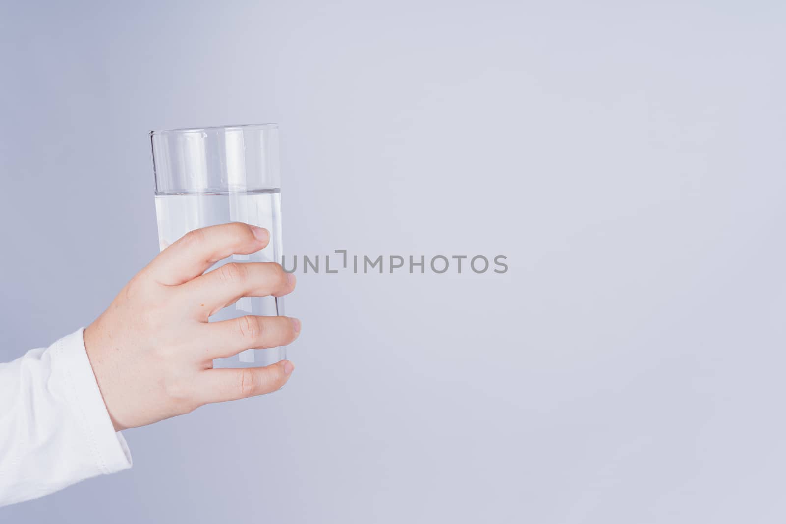 Close up Asian woman holding a glass of water in hand on grey background. Healthcare and medical pharmacy concept