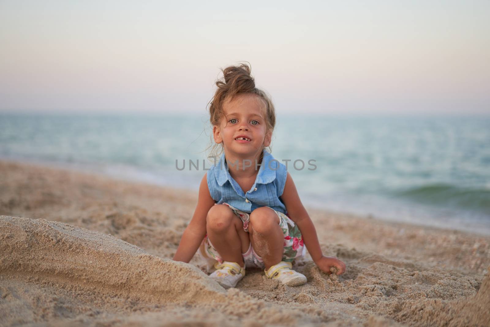 Child playing sand beach Little girl play sad alone summer family vacation Caucasian female 3 years old dressed denim near sea water