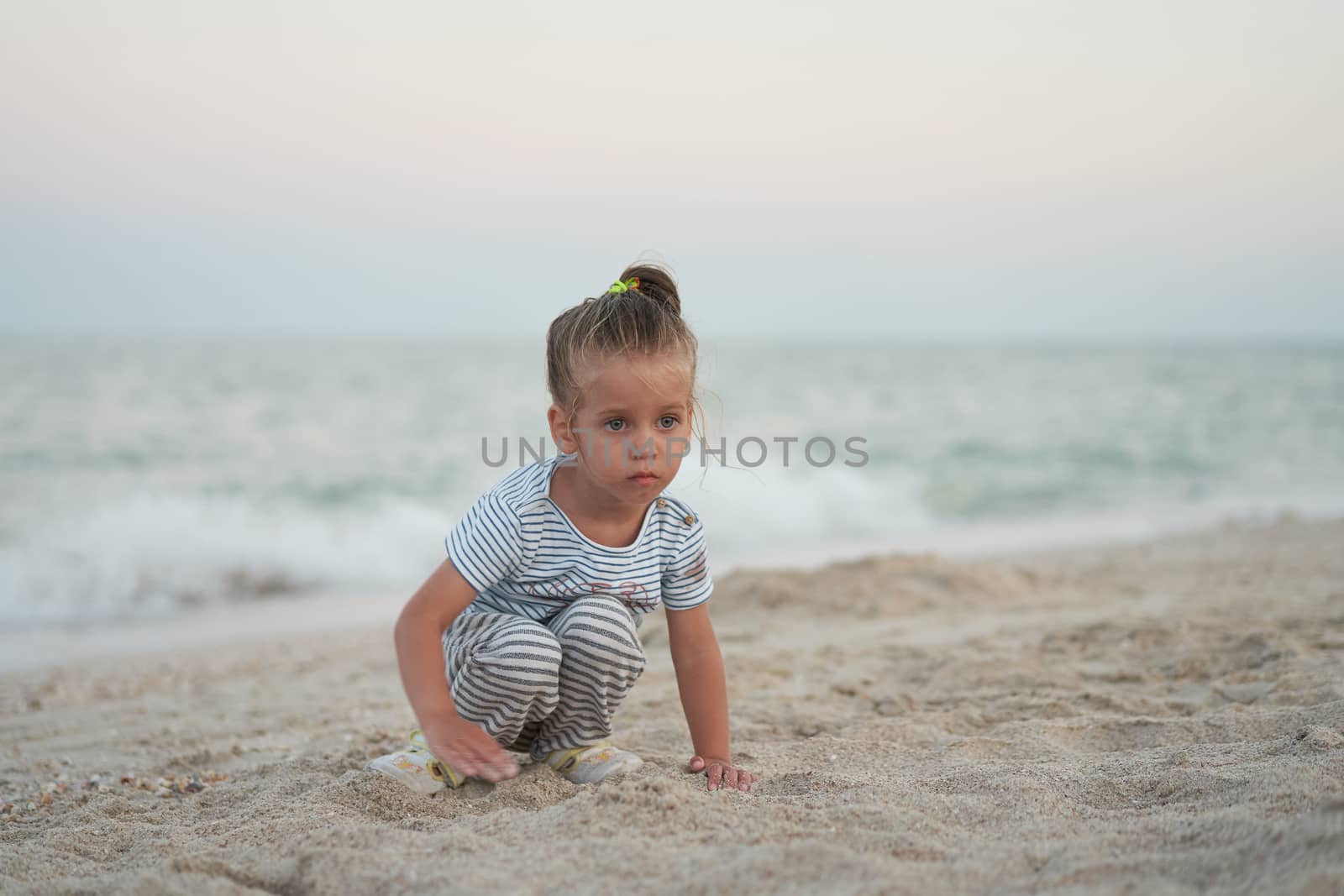 Child playing sand beach Little girl play sad alone summer family vacation Caucasian female 3 years old dressed denim near sea water