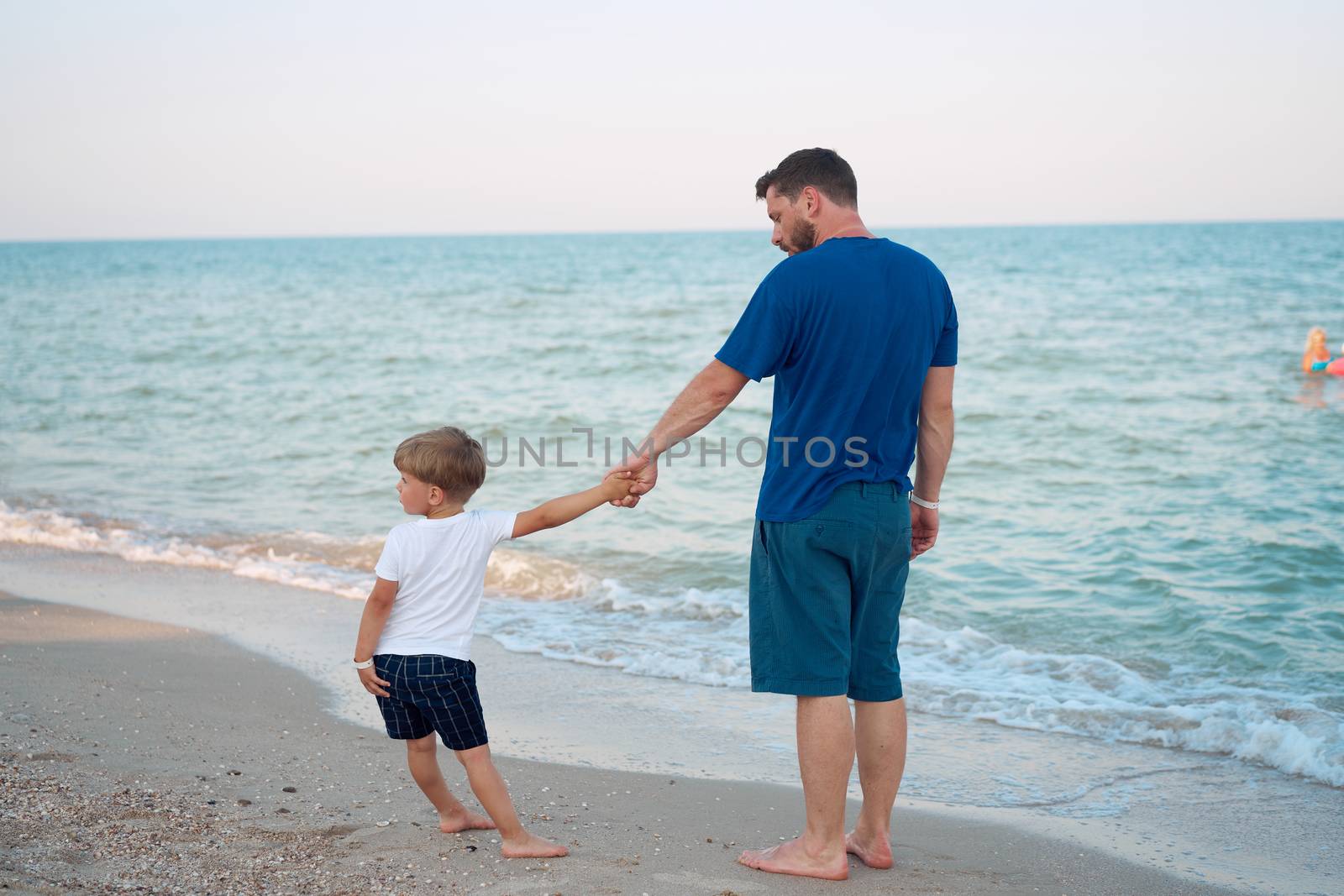 Dad holds son hand. Father Child spending time together sea vacation Young man little boy walking beach Fathers day. Family with one child. Happy childhood with daddy. Full lenght