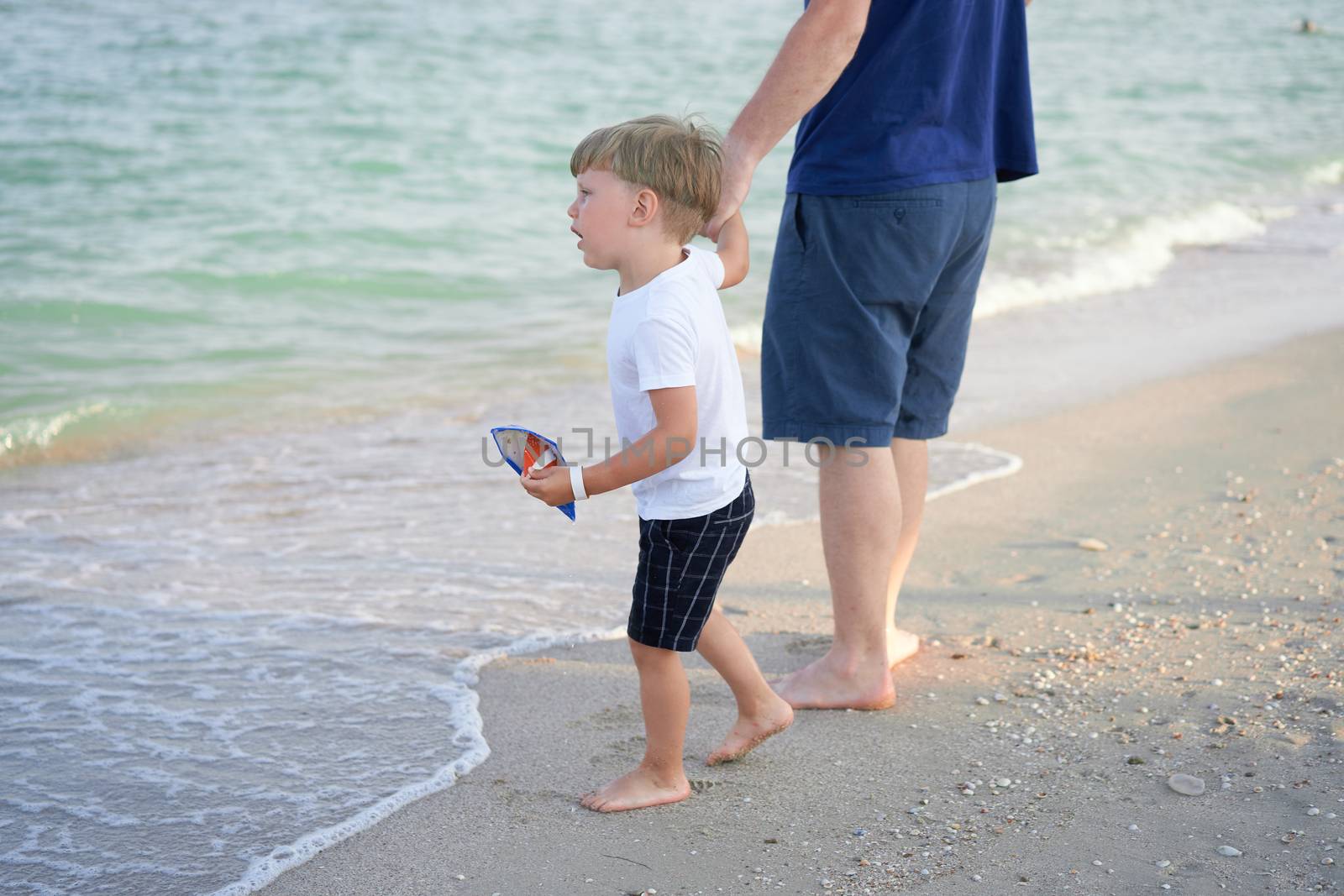 Dad holds son hand. Father Child spending time together sea vacation Young man little boy walking beach Fathers day. Family with one child. Happy childhood with daddy.