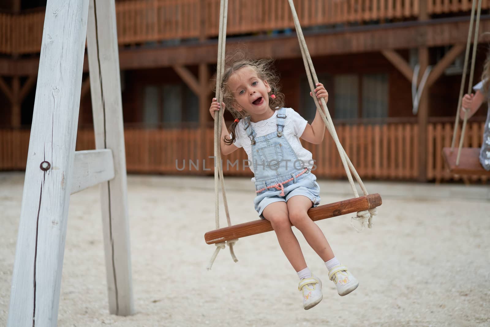 Playful kid swinging swing. Joyful little girl play having fun playground summertime Enjoyment outside. Summer children leisure. Preschool lifestyle