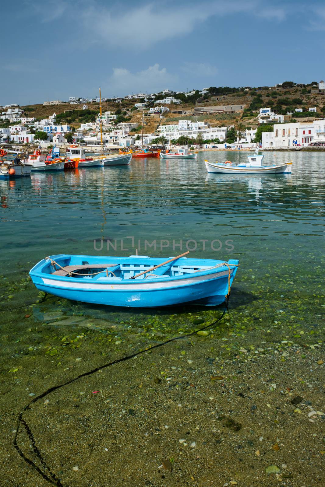 Greek fishing boat in clear sea water in port of Mykonos. Chora town, Mykonos, Greece