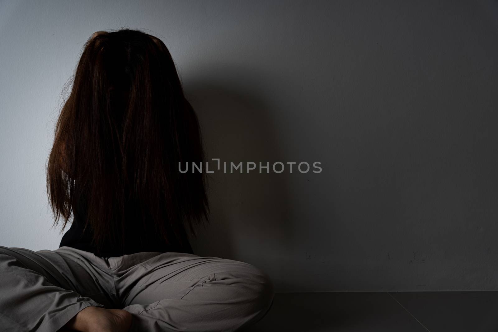 sad woman hug her knee and cry sitting alone in a dark room. Depression, unhappy, stressed and anxiety disorder concept. by mikesaran