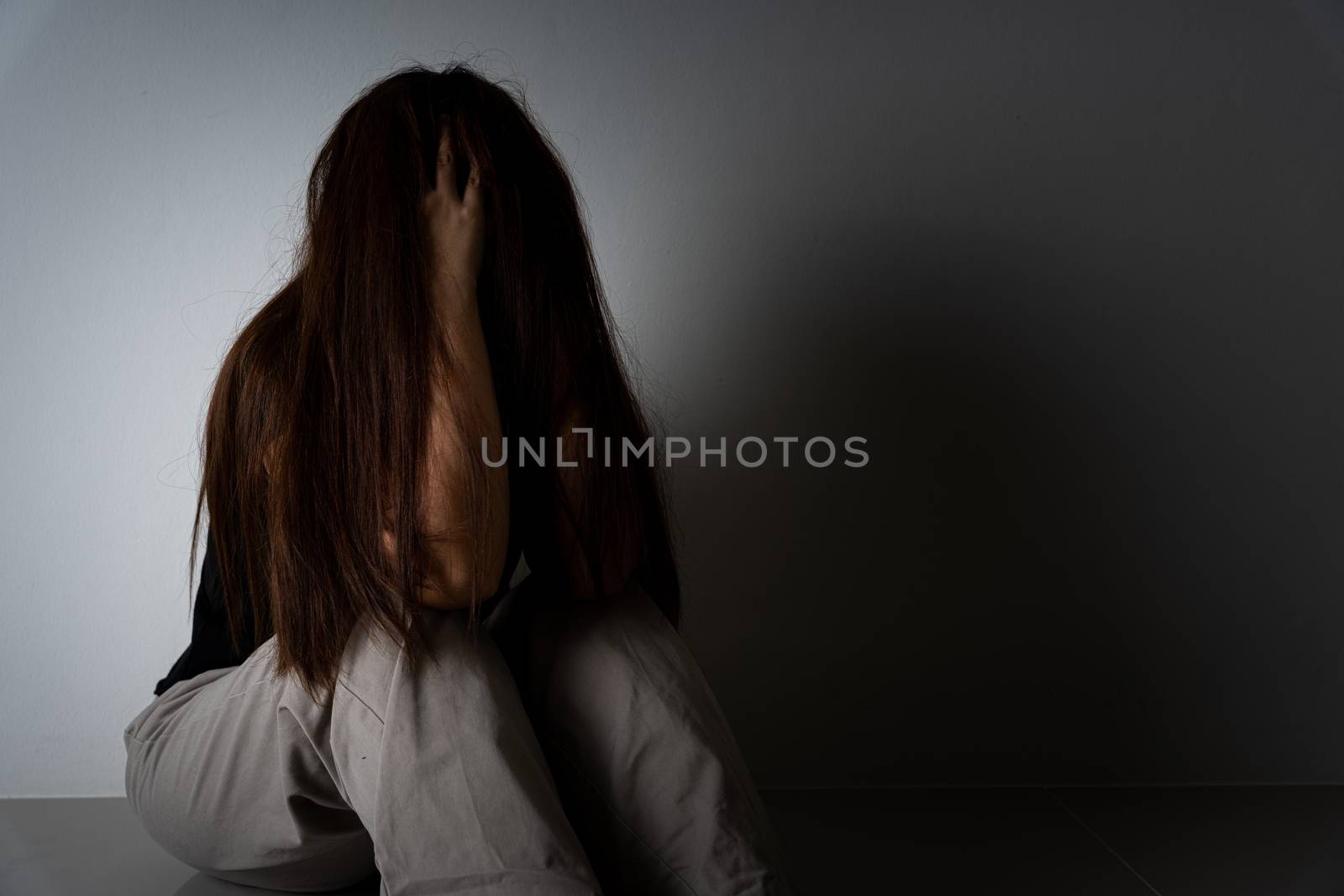 sad woman hug her knee and cry sitting alone in a dark room. Depression, unhappy, stressed and anxiety disorder concept. by mikesaran