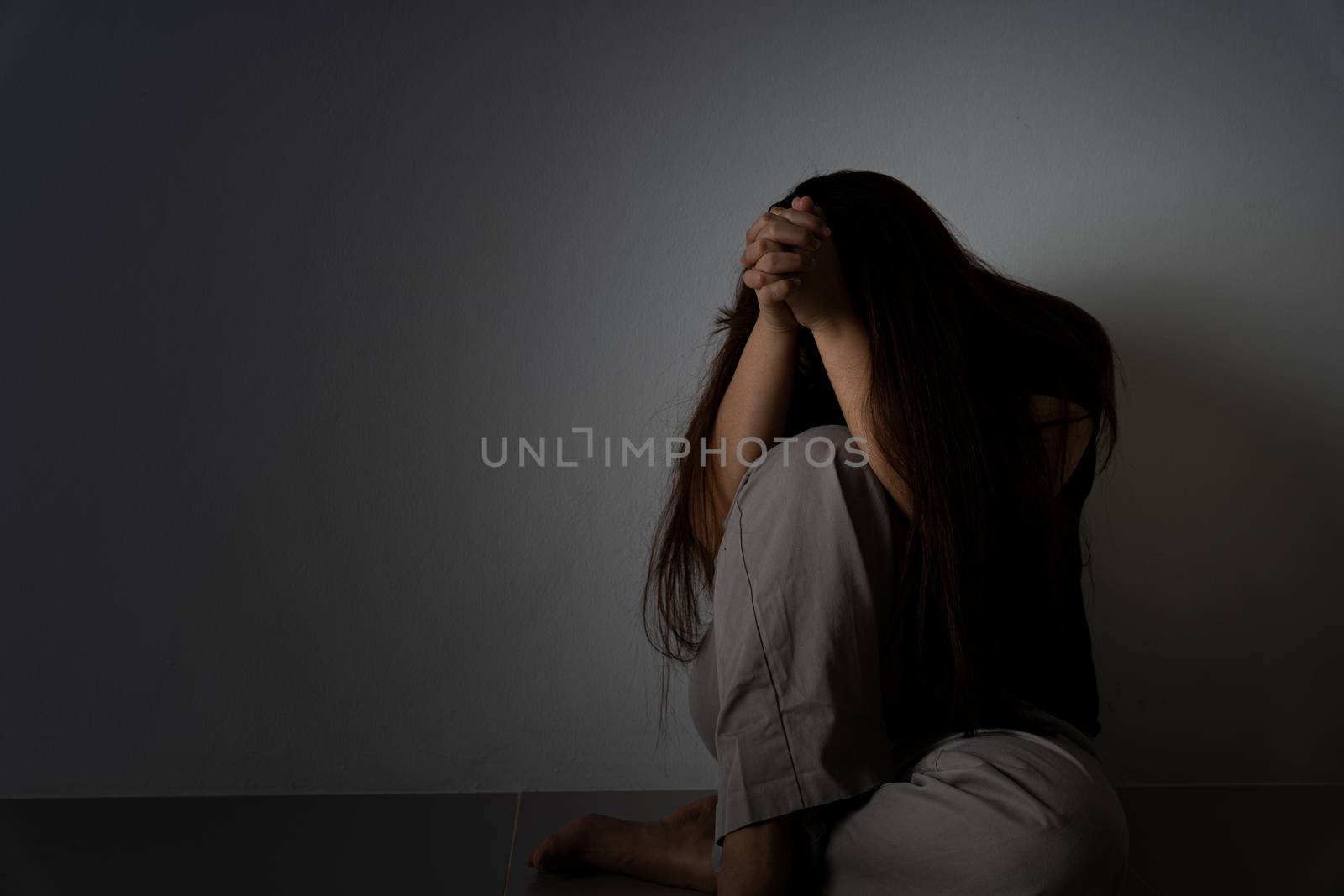 sad woman hug her knee and cry sitting alone in a dark room. Depression, unhappy, stressed and anxiety disorder concept. by mikesaran