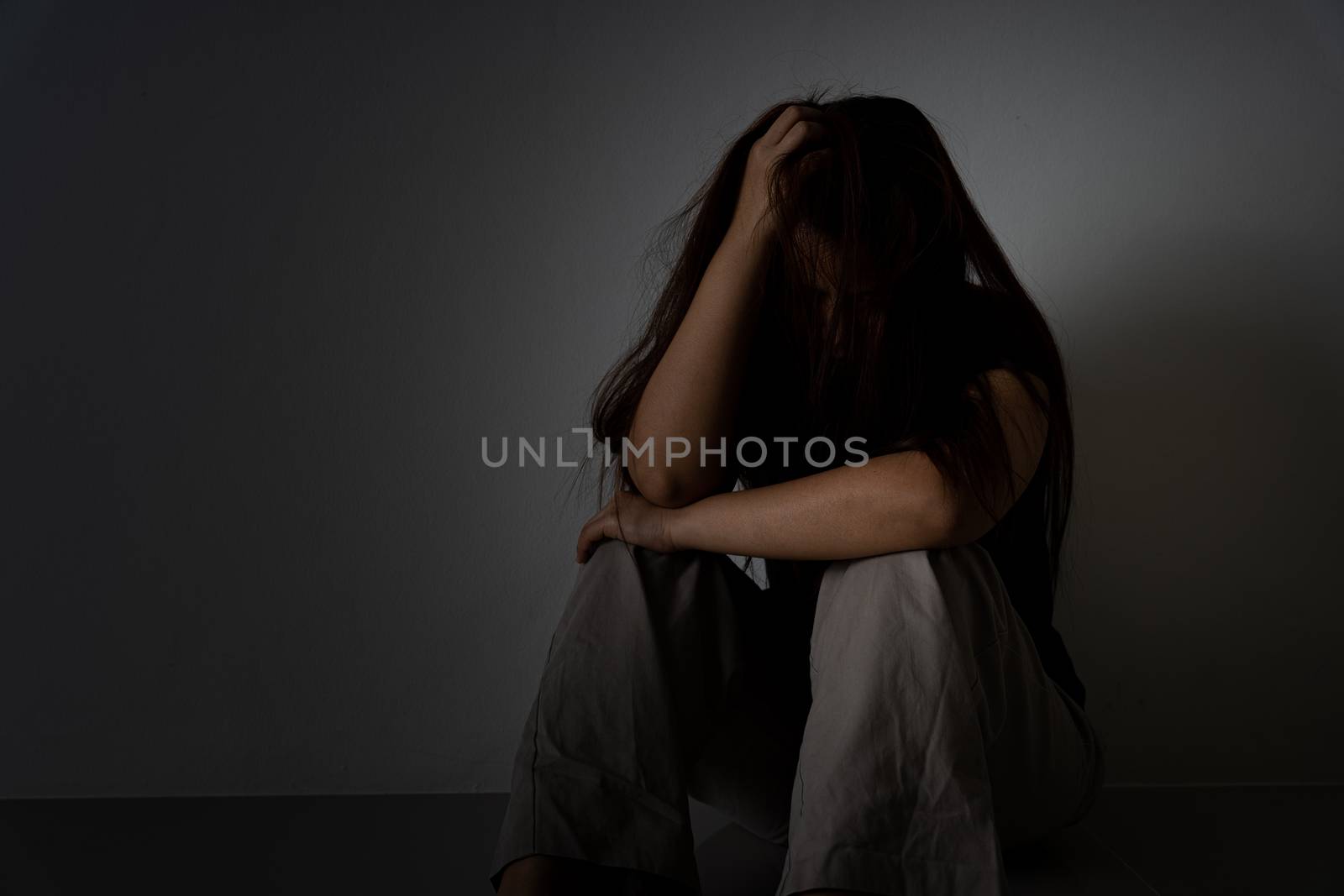 sad woman hug her knee and cry sitting alone in a dark room. Depression, unhappy, stressed and anxiety disorder concept. by mikesaran