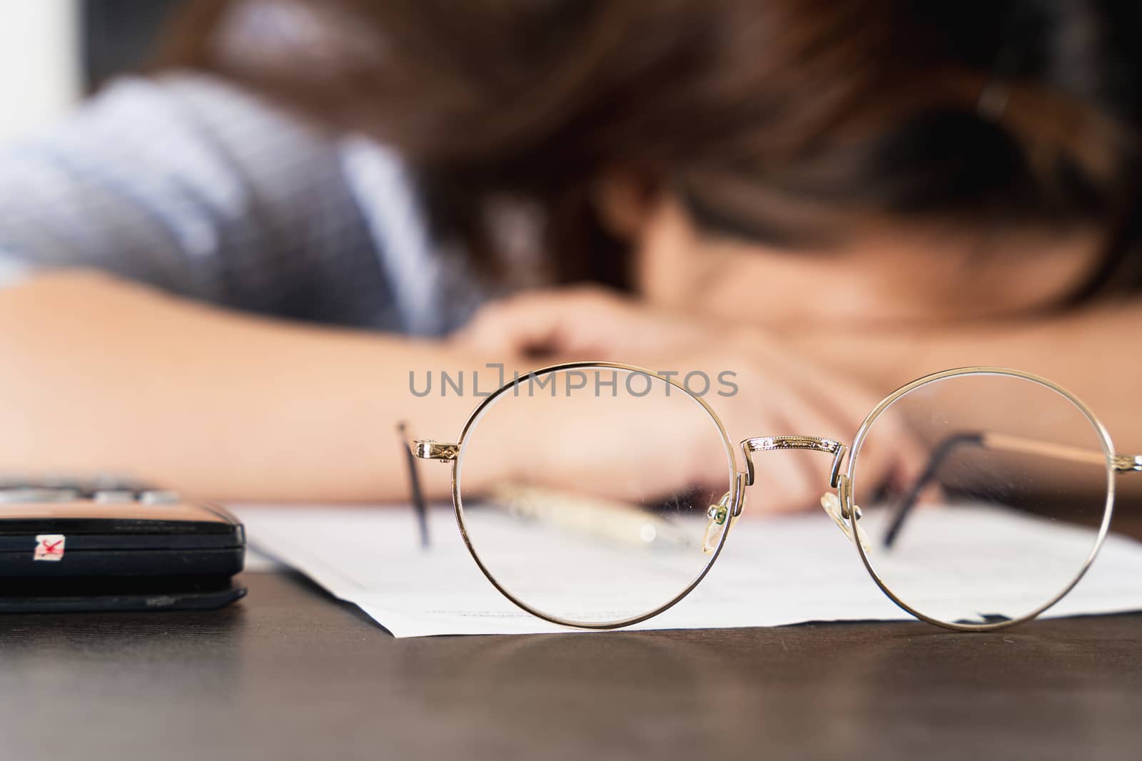 Close up coins on the desk with businesswoman working on desk office with depression, unhappy and stressed emotion. Expenses, taxes, home budget finance accounting concept. by mikesaran