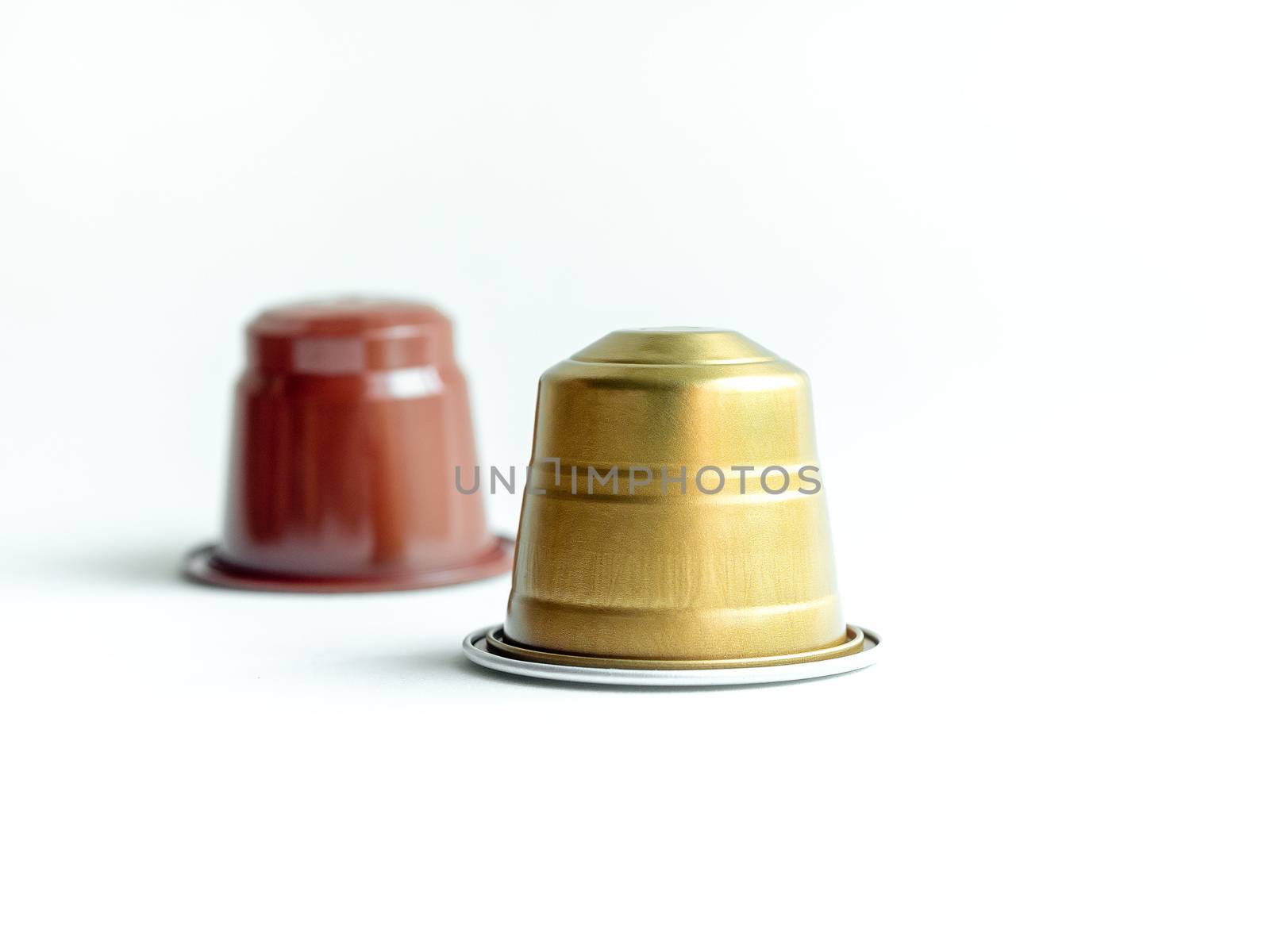 Gold and brown espresso coffee capsules on white background.