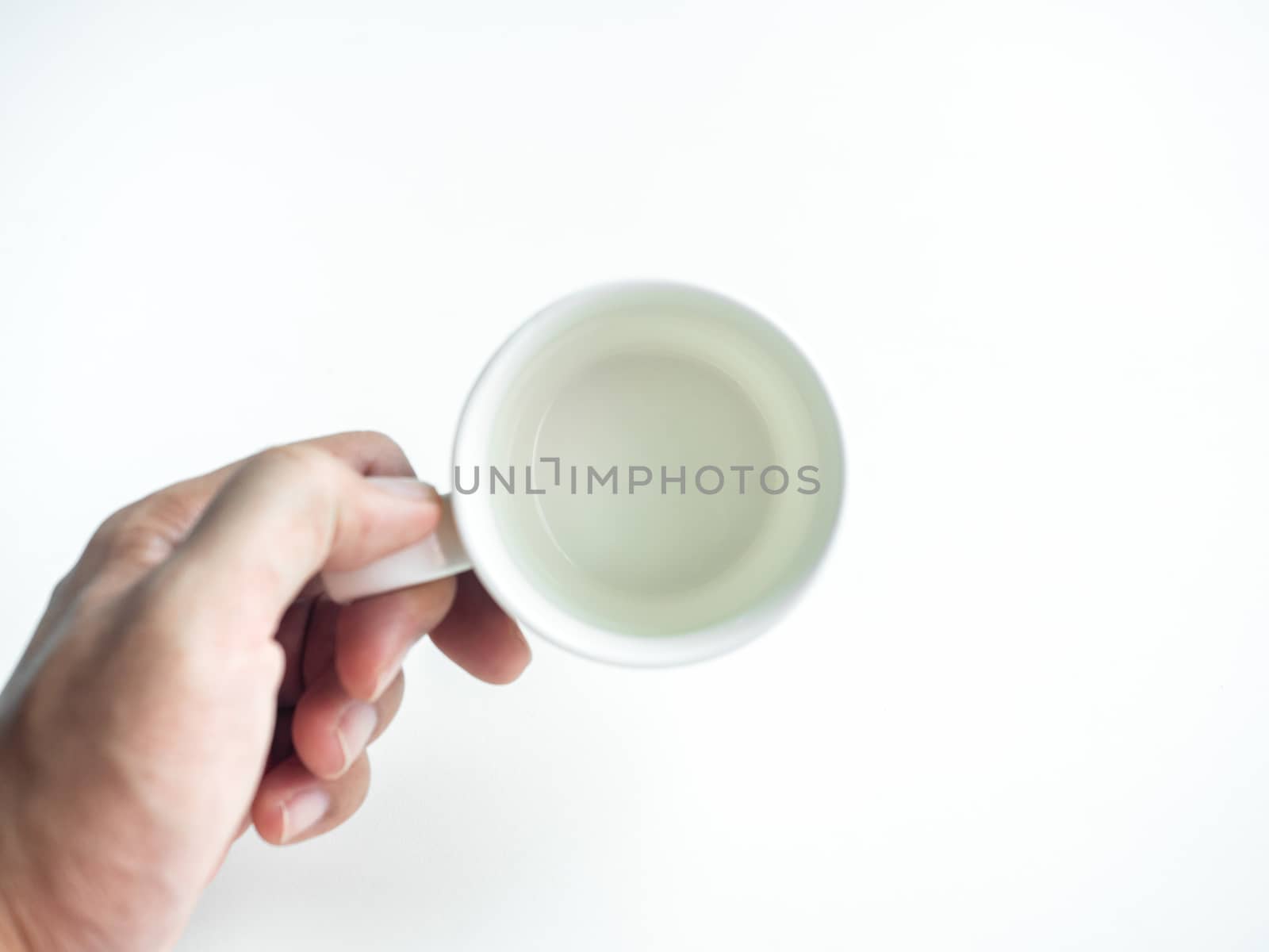 Empty white clean ceramic coffee cup in hand isolated on white background, top view. Hand holding blank round cup.