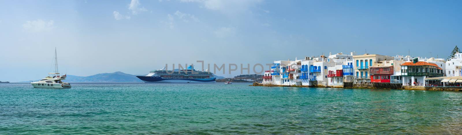 Scenic Little Venice houses in Chora Mykonos town with yacht and cruise ship. Mykonos island, Greecer