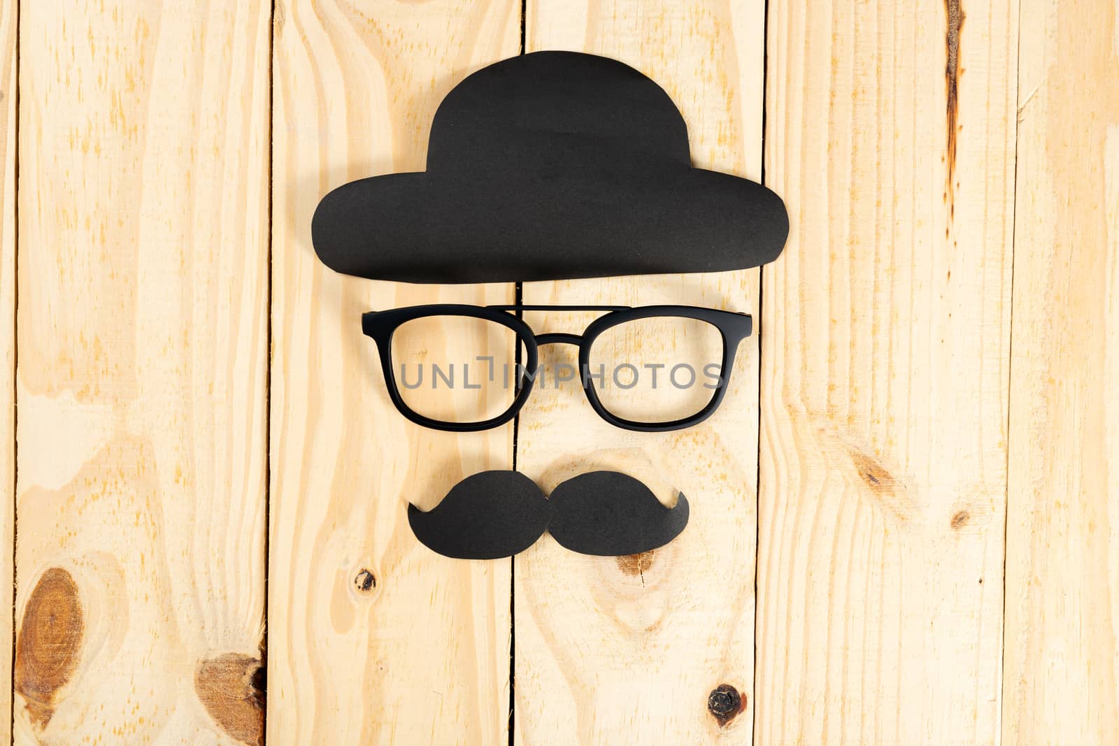 Happy Father Day background concept with glasses, black hat and black mustache on wooden background with copy space for text.