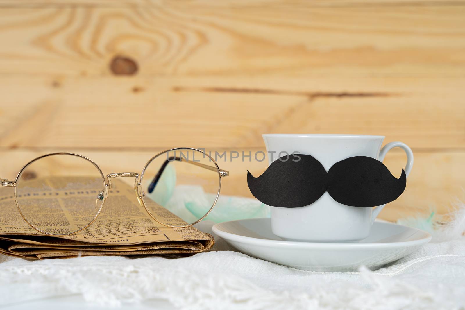 Happy Father Day background concept with and cup of tea, black mustache, glasses and newspaper on wooden background with copy space for text.