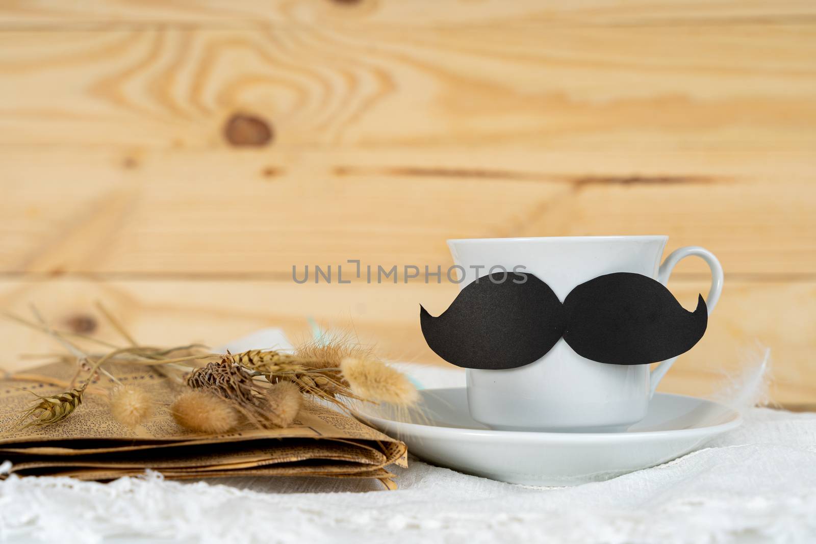 Happy Father Day background concept with and cup of tea, black mustache and dry grass flower on wooden background with copy space for text.