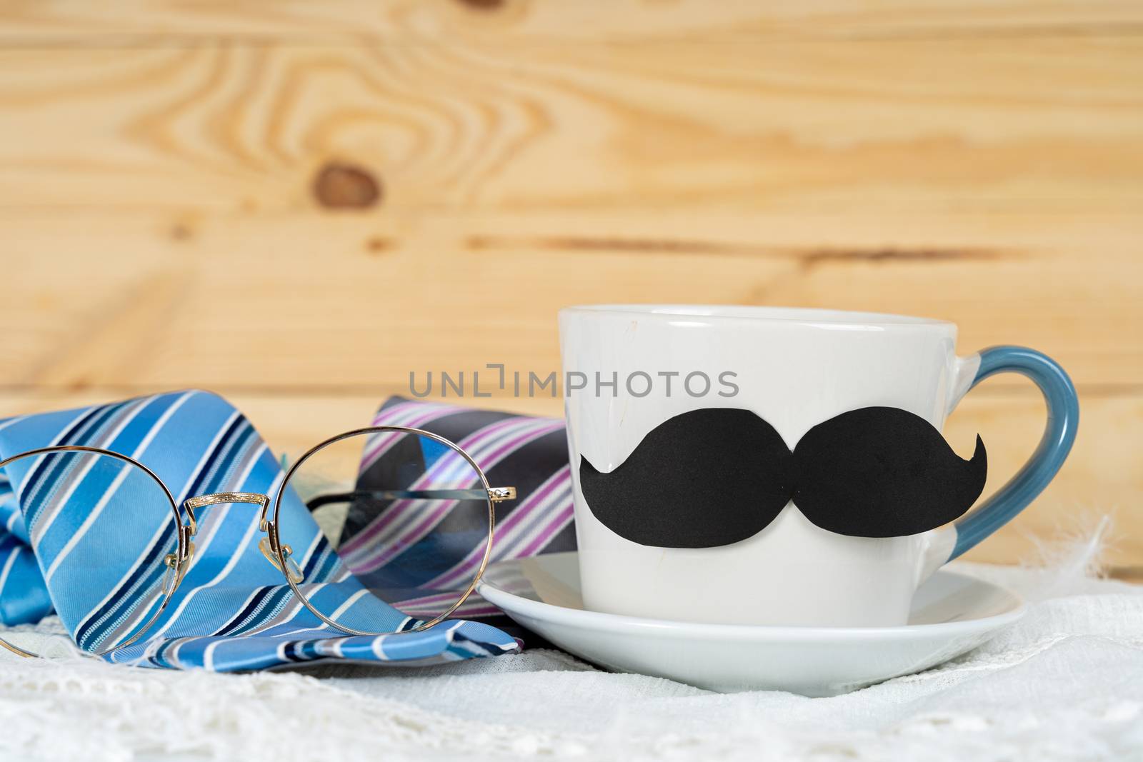 Happy Father Day background concept with and cup of tea, black mustache and blue and pink necktie on wooden background with copy space for text.