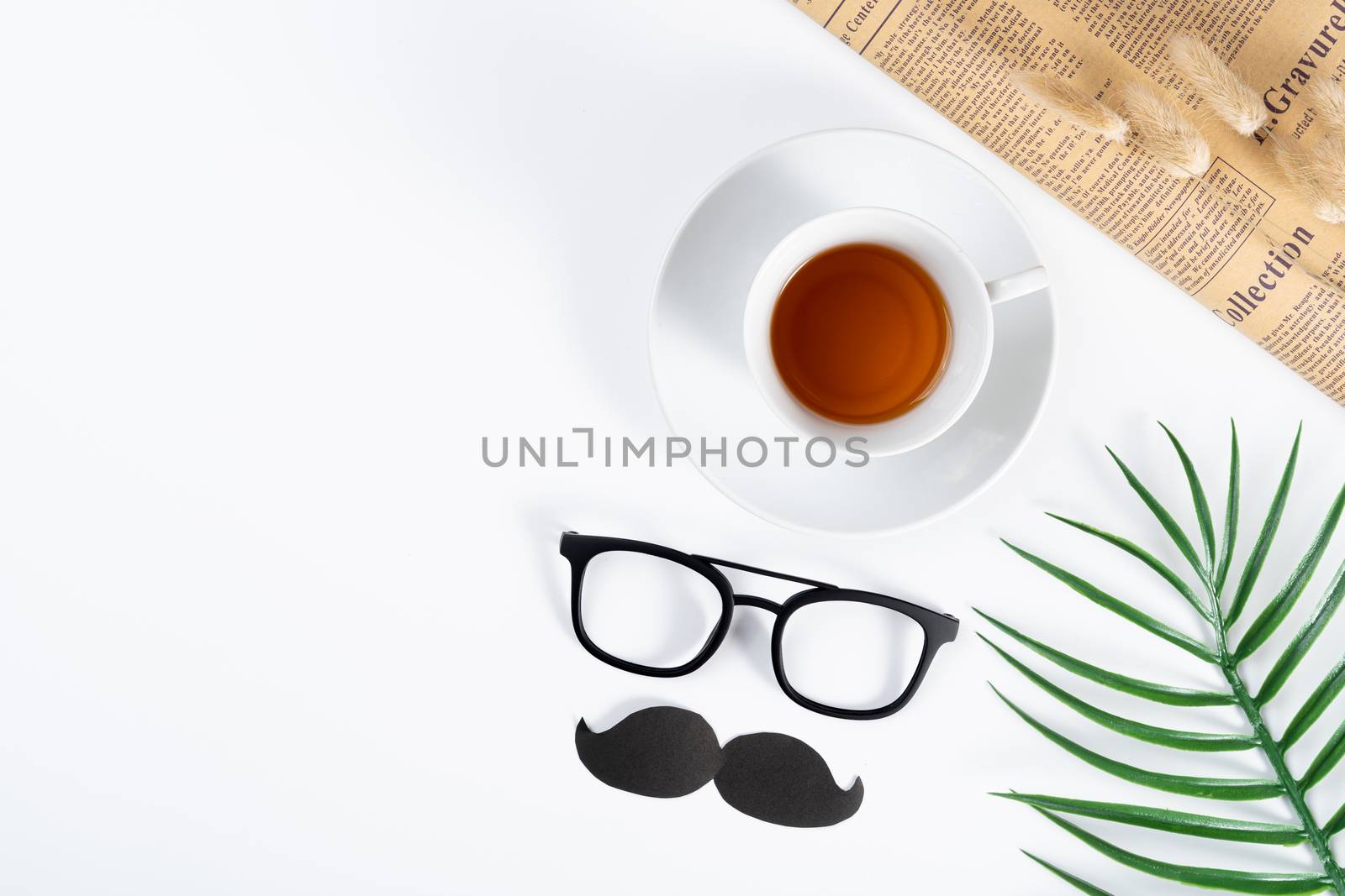 Happy Father Day background concept with newspaper, leaf, black mustache, glasses and cup of tea on white background with copy space for text.