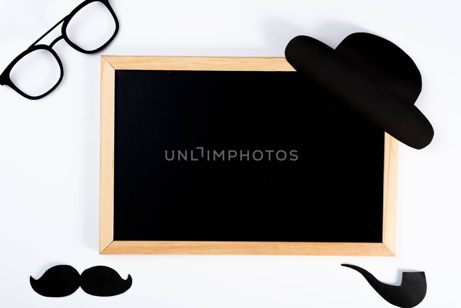 Happy Father Day background concept with blackboard and paper cut of hat, glasses, black mustache and smoking pipe on white background with copy space for text.