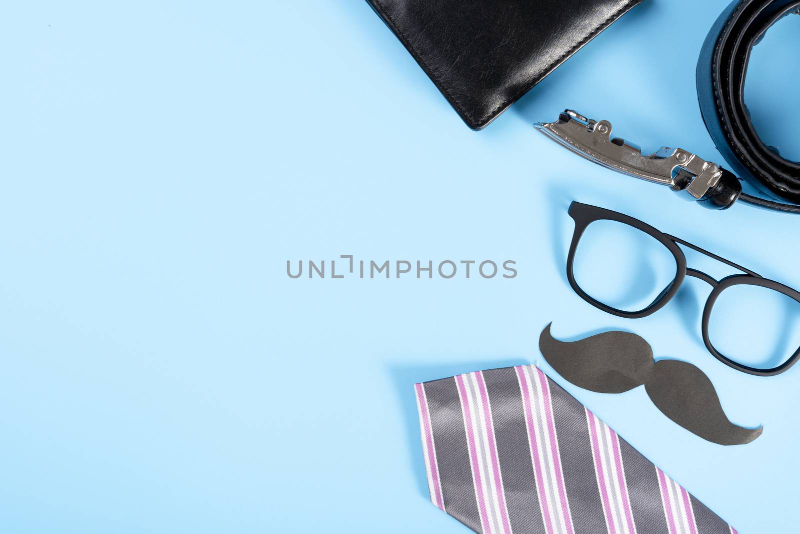 Happy Father Day background concept with pink necktie, glasses, wallet, belt and black mustache on blue background with copy space for text.