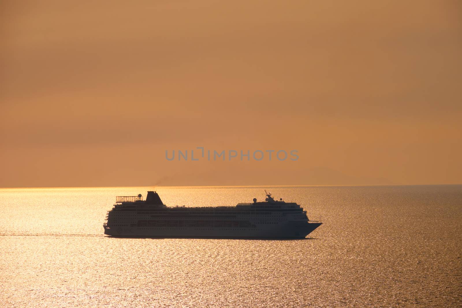 Cruise ship silhouette in Aegean sea on sunset. Mykonos island, Greece