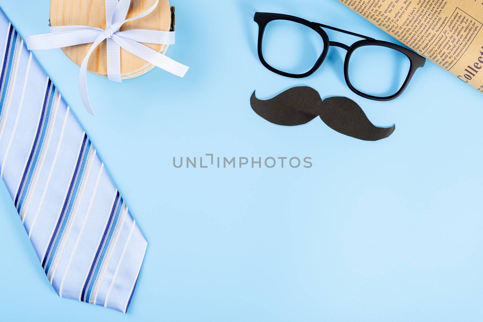 Happy Father Day background concept with blue necktie, glasses, gift box and black mustache on blue background with copy space for text.