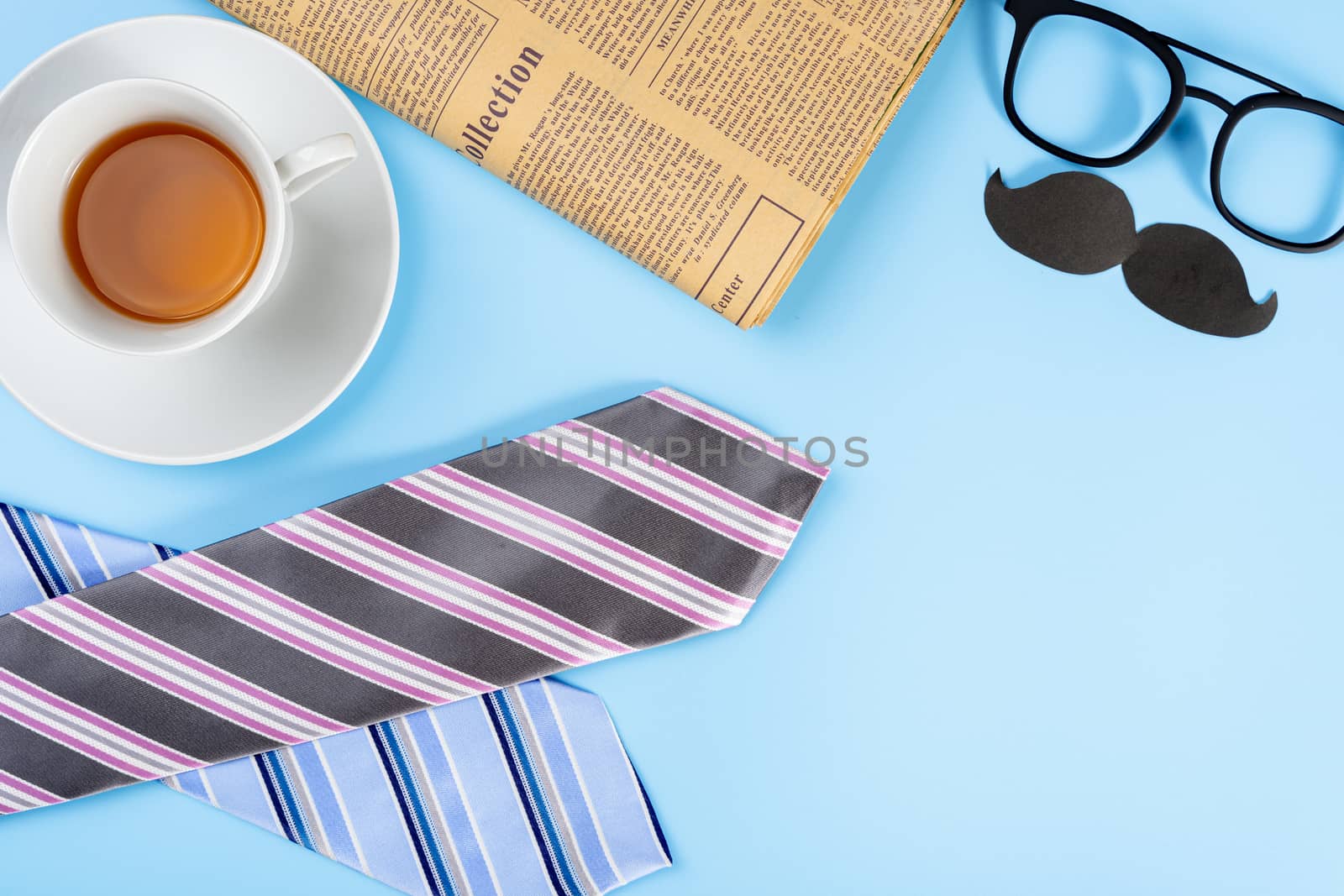 Happy Father Day background concept with blue and pink necktie, glasses, newspaper, cup of tea and black mustache on blue background with copy space for text.