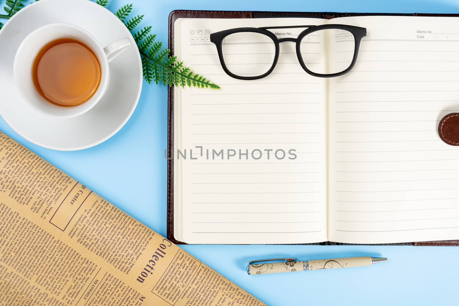 Happy Father Day background concept with notebook, pen, leaf, cup of tea, glasses and newspaper on blue background with copy space for text.
