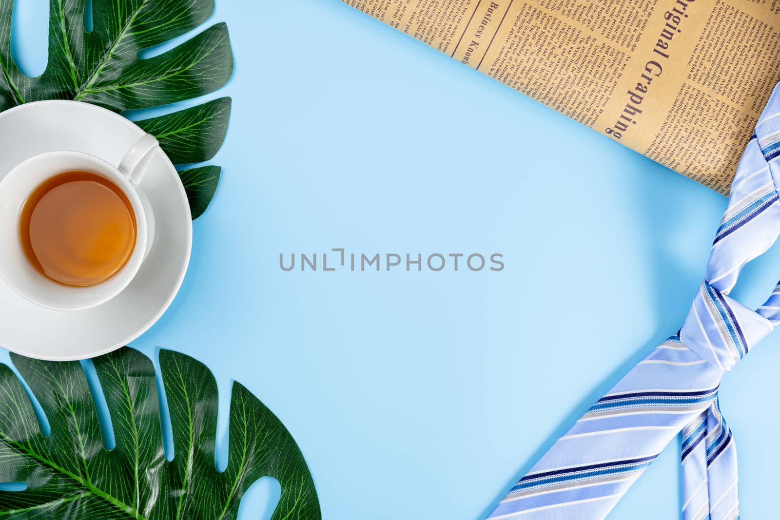 Happy Father Day background concept with blue necktie, newspaper, leaf and cup of tea on blue background with copy space for text.
