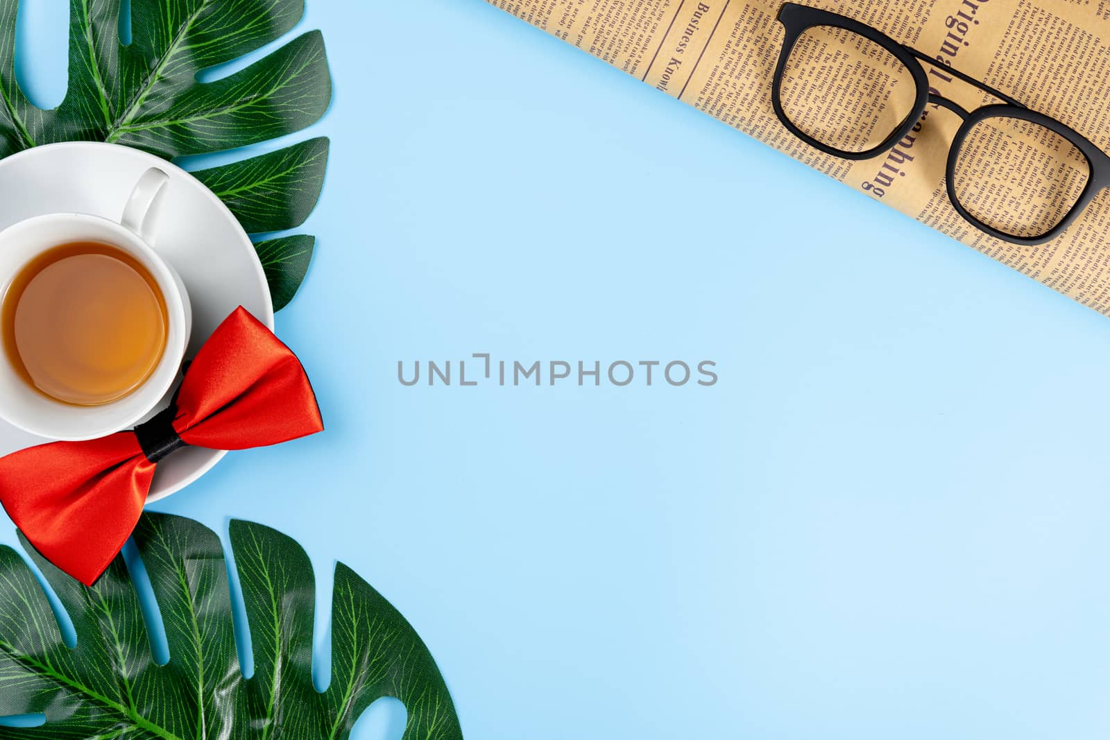 Happy Father Day background concept with blue necktie, newspaper, glasses, red ribbon and cup of tea on blue background with copy space for text.