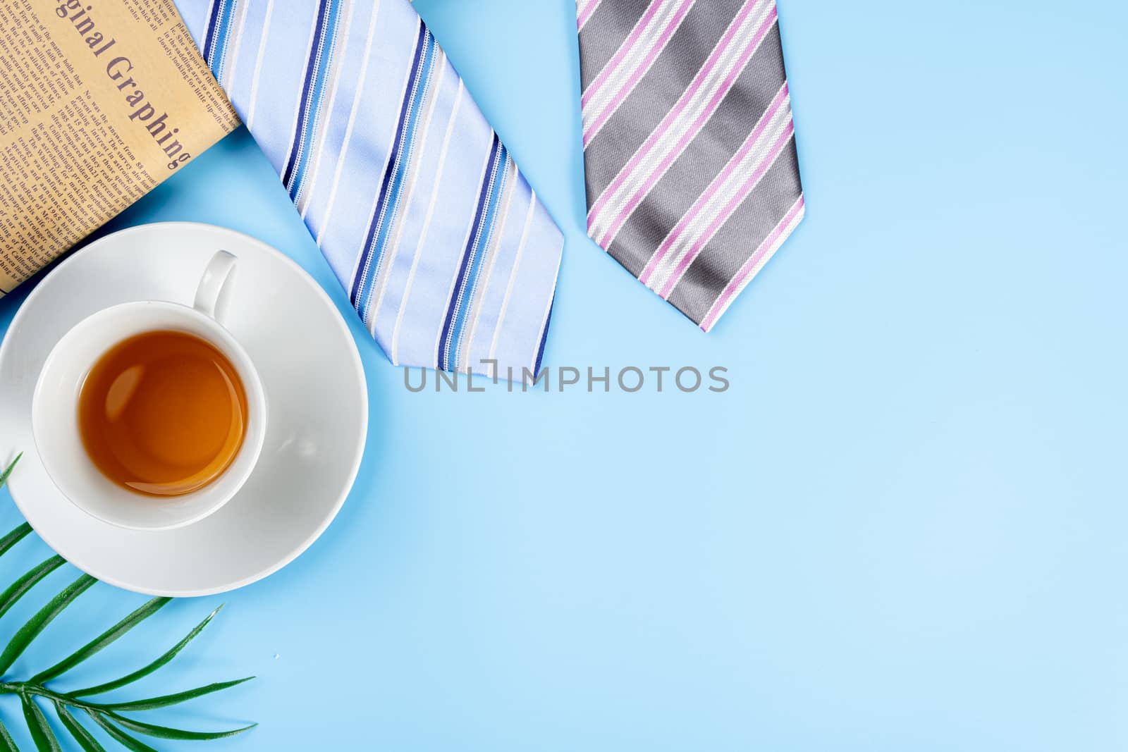 Happy Father Day background concept with blue and pink necktie, newspaper, leaf and cup of tea on blue background with copy space for text.