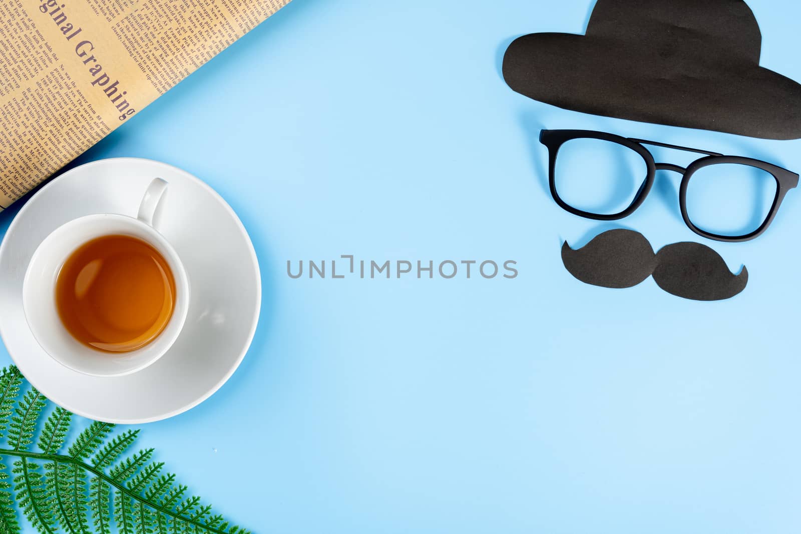 Happy Father Day background concept with glasses, black mustache, hat, newspaper, leaf and cup of tea on blue background with copy space for text.