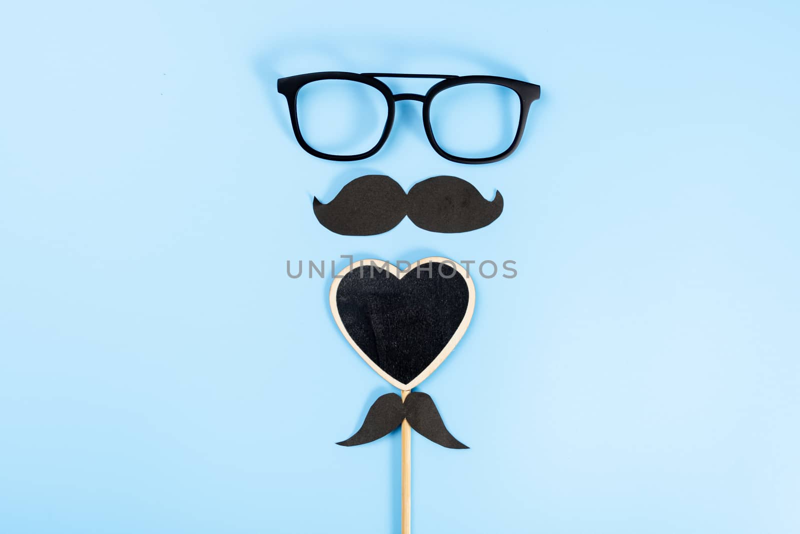 Happy Father Day background concept with glasses, black heart shape and black mustache on blue background with copy space for text.